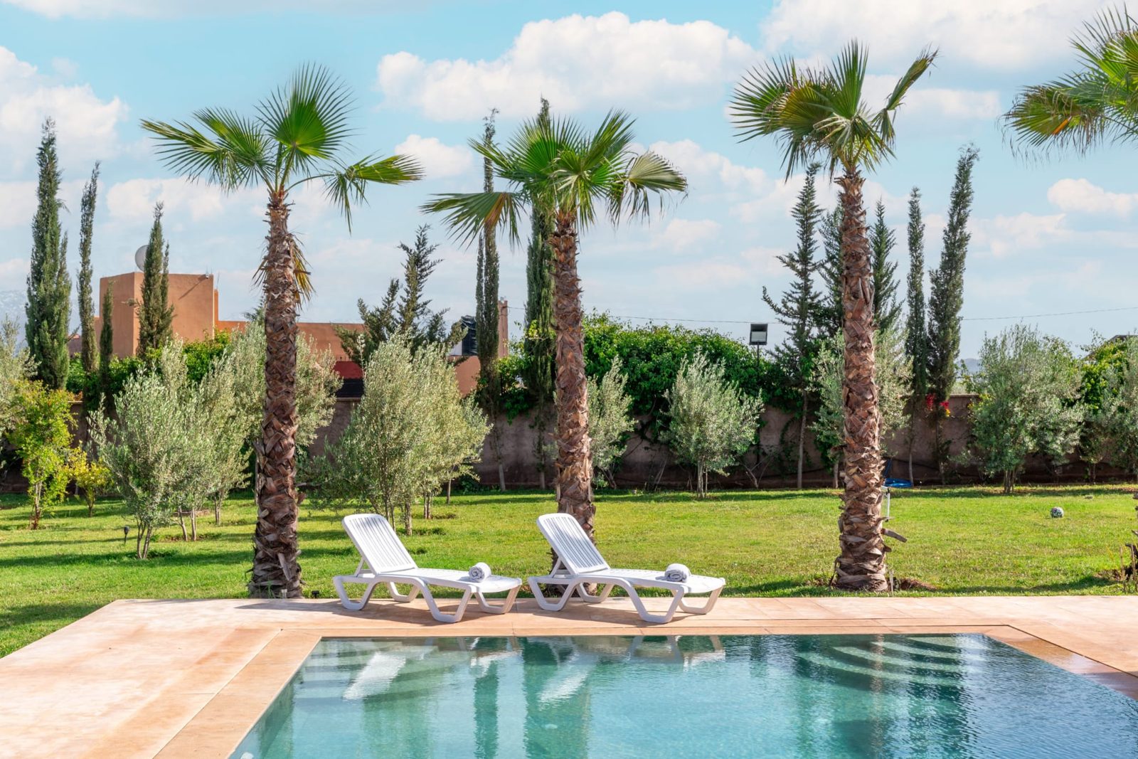 Ligbedden en palmbomen bij het zwembad — Villa Sakinah Marrakech